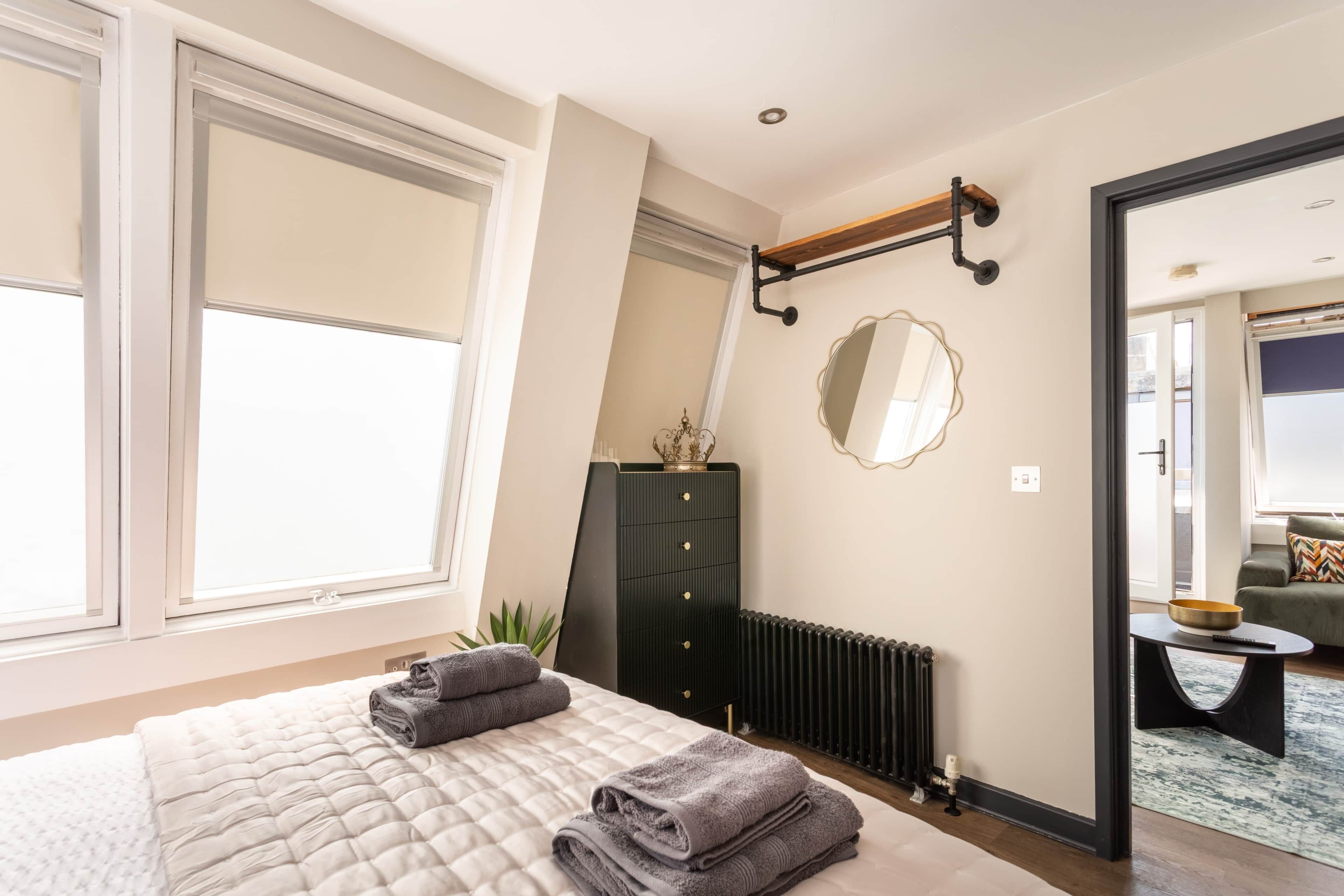 A bedroom with a bed, a dresser, a mirror, and a radiator.
