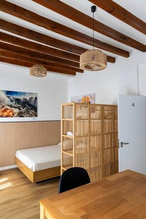 Ein Zimmer mit einem Bett, einem Holzkasten, einem Tisch und einer Tür mit der Nummer 4.