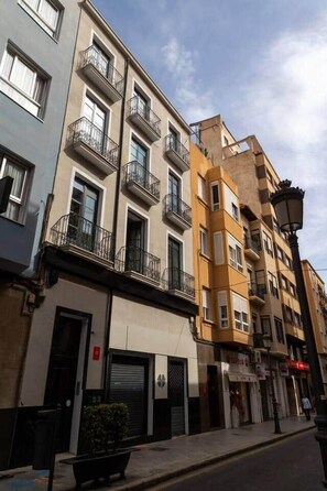 A multi-story building with balconies, a closed shop, and a street lamp. - Suite 1 Apartment, Teatro24 (Alicante)