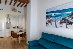 A modern kitchen with marble countertops, a dining area with a table and chairs, and a large ocean view painting on the wall. - Suite 1 Apartment, Teatro24 (Alicante)