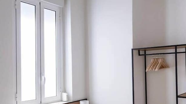 Una camera da letto con un letto, una finestra, un comodino, una lampada e un armadio.