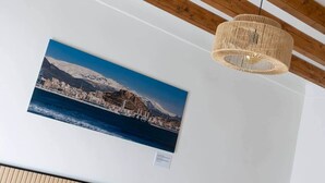 Een foto van een kuststad met bergen, een houten plafond en een geweven lamp.