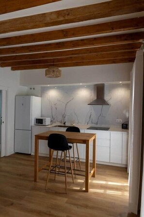 A modern kitchen with white cabinets, a wooden ceiling, and a dining area with a table and chairs. - Suite-Studio 6 Apartment at Teatro24 (Alicante)