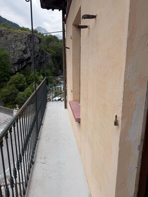 A balcony with a view of a rocky mountain and a river.