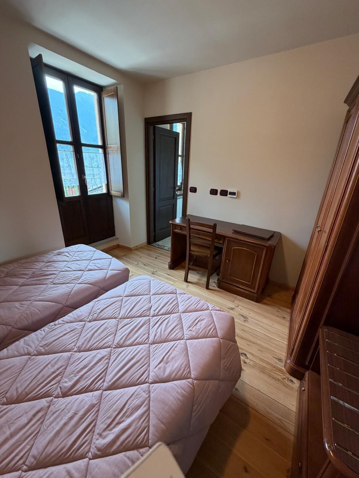 Un dormitorio con dos camas, un escritorio y un armario.