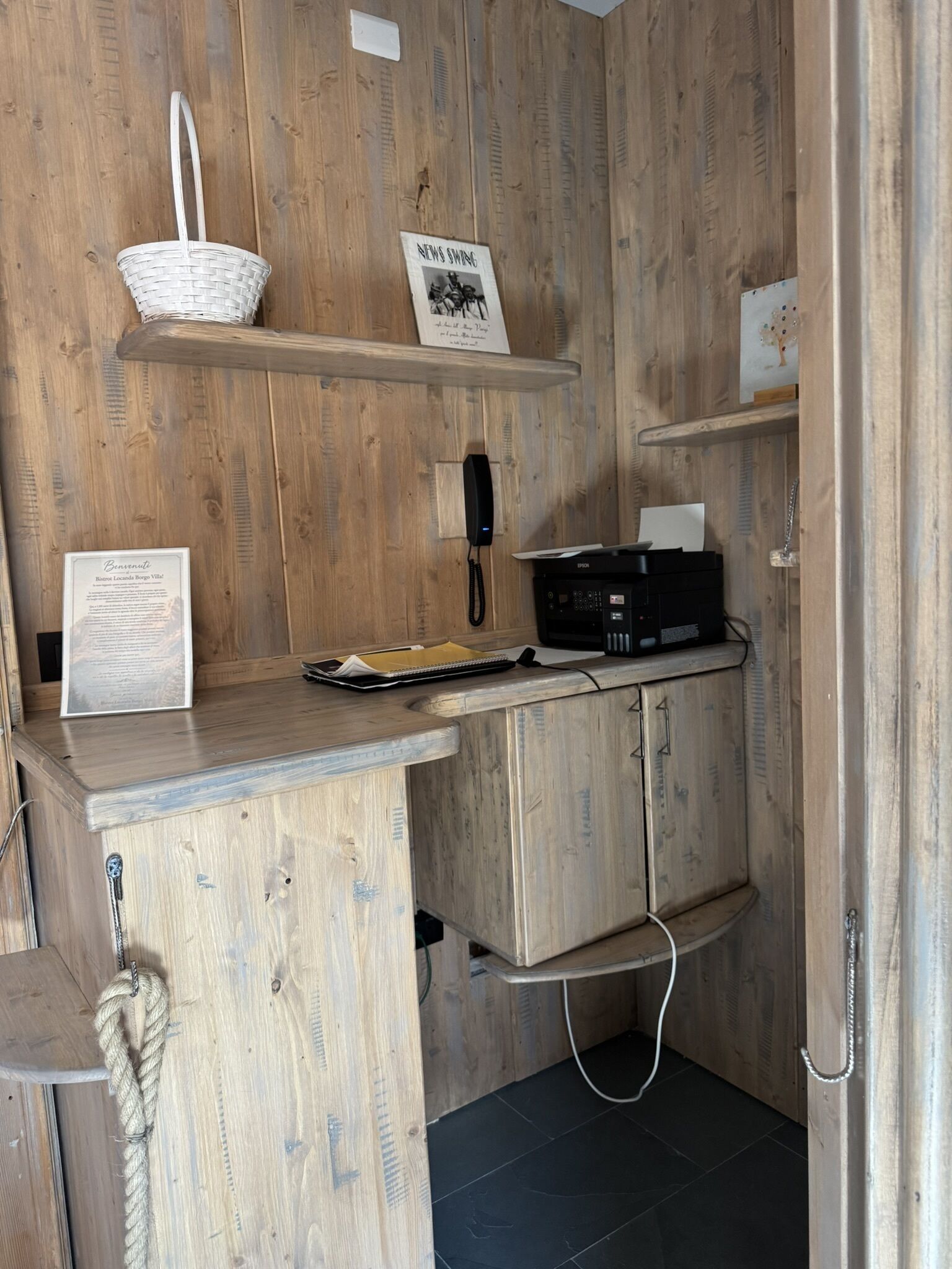 Ein Holzinterieur mit einem Empfangsbereich, einem Telefon, einem Korb und einem Schild.