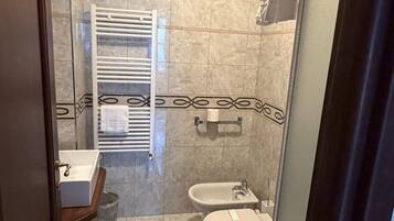 A bathroom with a toilet, bidet, and a towel rack.