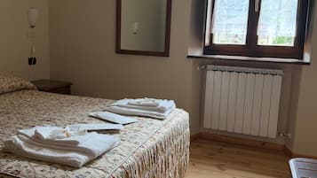 Une chambre à coucher avec un lit, une fenêtre, un radiateur et un miroir au mur.