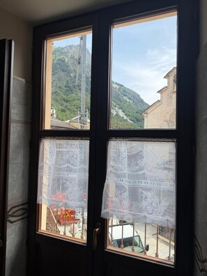 A window with lace curtains, a view of a mountain, and a construction site.