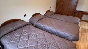 Un dormitorio con dos camas, un armario de madera y una lámpara de pared.