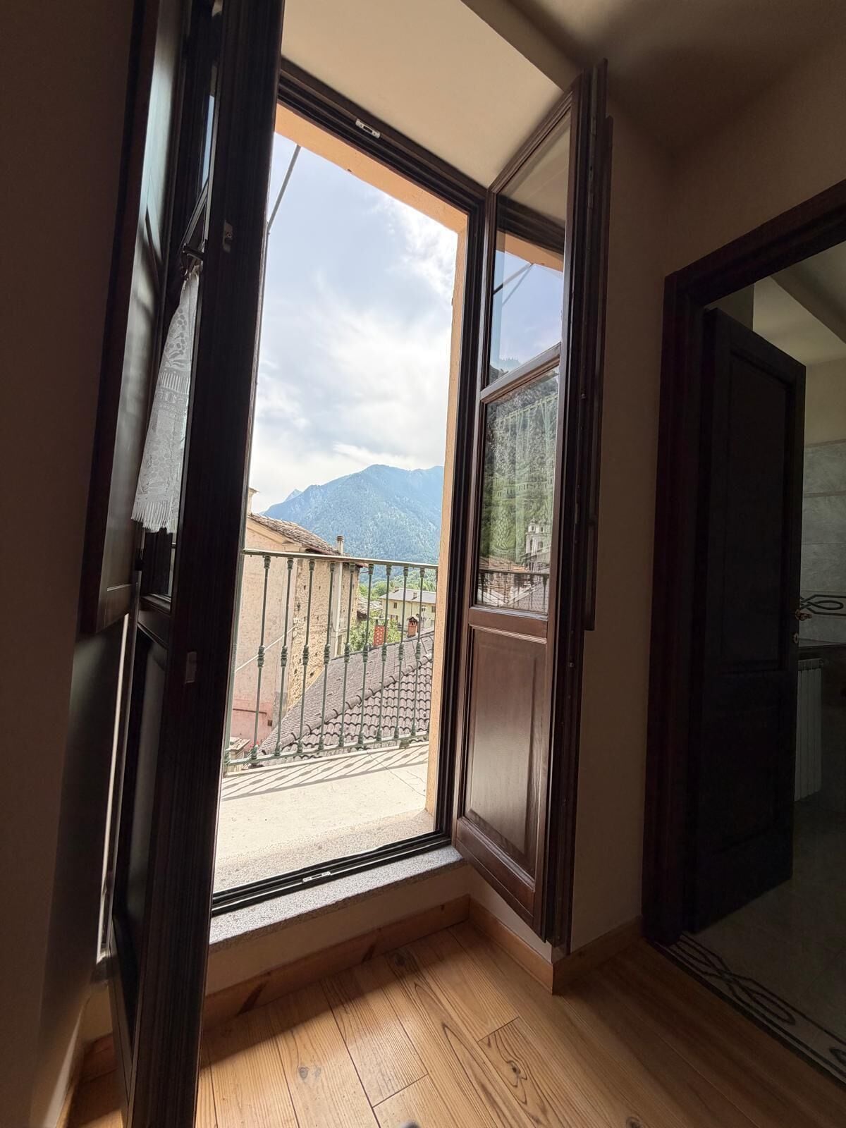 An open window with a view of mountains and a balcony.