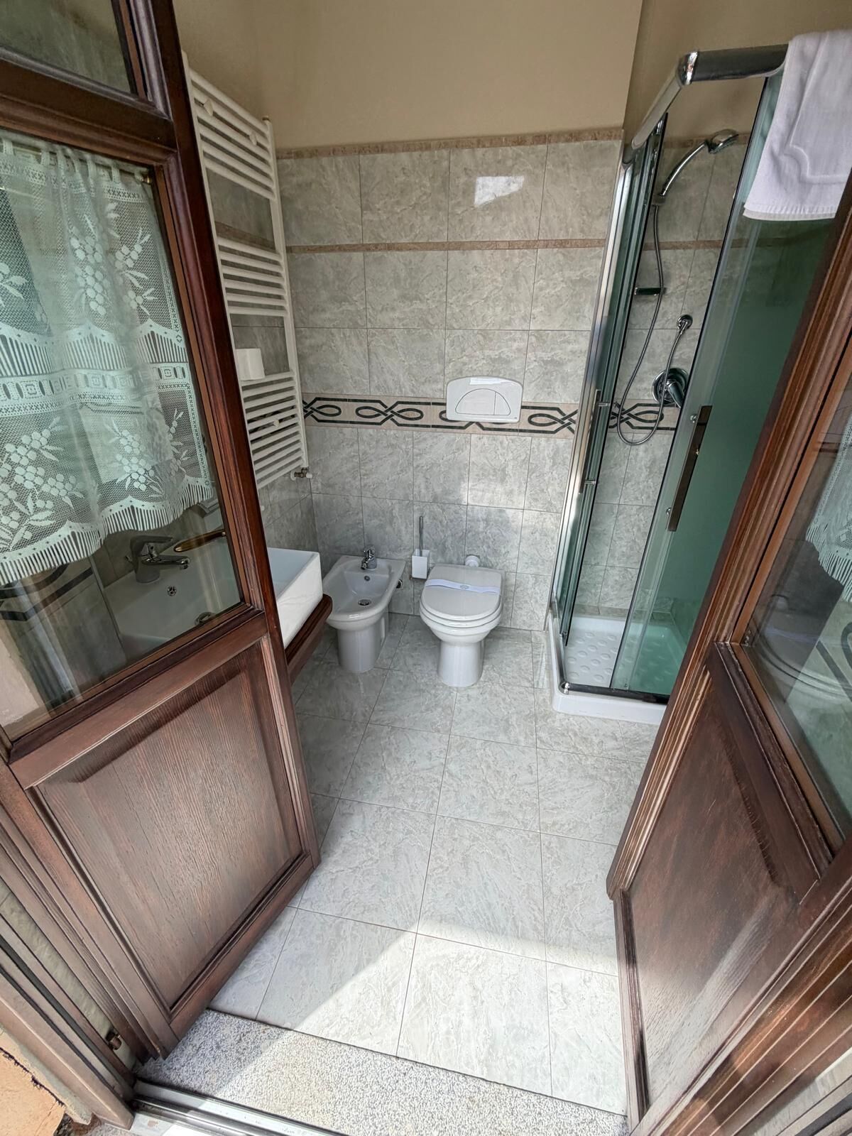 A bathroom with a glass shower enclosure, a sink, and two toilets.
