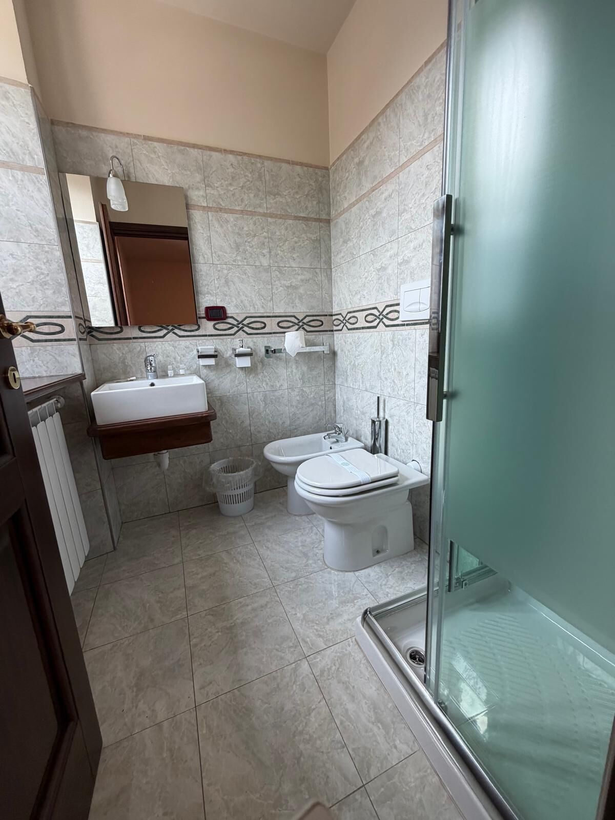 Een badkamer met een douche, twee wasbakken, een toilet en een bidet.
