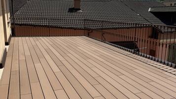 A wooden deck with a metal railing, overlooking a mountainous landscape.