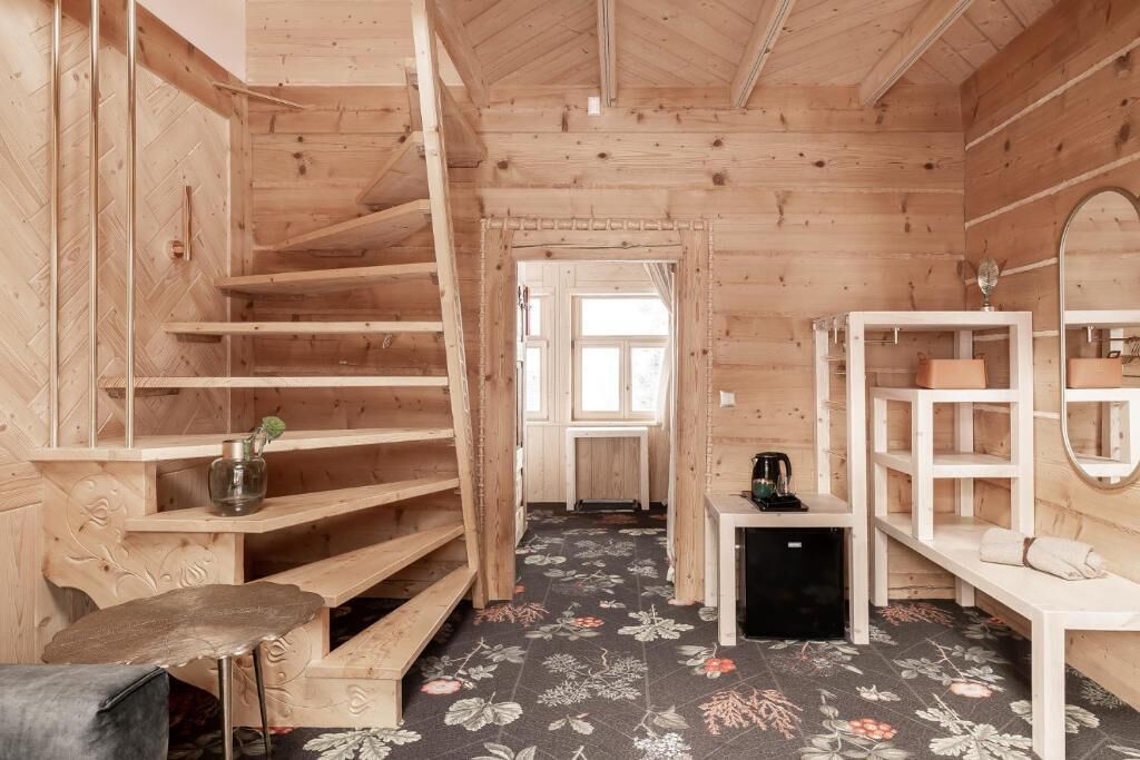 A wooden interior with a staircase, a small table with a kettle, and a bench.