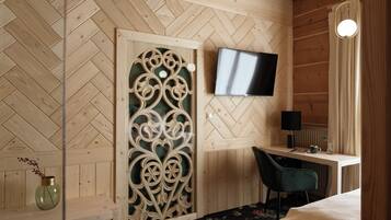 Un intérieur en bois avec un téléviseur fixé au mur, un bureau avec une chaise et une cloison décorative en bois.