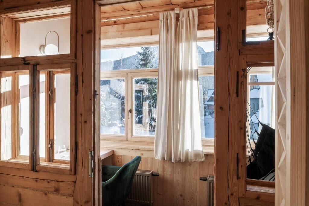 Ein Holzhütten-Interieur mit großen Fenstern, einer Heizung und einem Sessel.