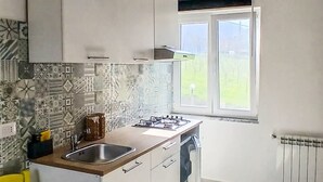 A modern kitchen with a central island, a yellow chair, and a window providing a view of the outdoors.
