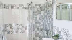 A bathroom with a toilet, bidet, shower, and vanity with a mirror.