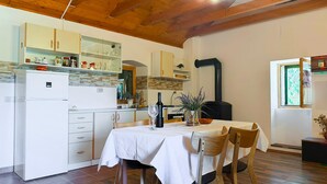 A kitchen with wooden beams, a dining table with chairs, and a window with a view. - 1 bedroom lovely home in Korusce (Korusce)