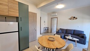 Een moderne keuken met een inbouwkoelkast, een eettafel met stoelen, een grijze bank en een klein bijzettafeltje.