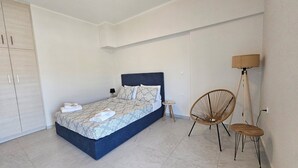 Een slaapkamer met een bed, een stoel, een lamp en een kledingkast.