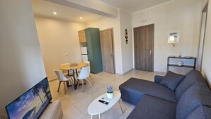 Een moderne woonkamer met een bank, een salontafel, een televisie en een eethoek met stoelen en een tafel.