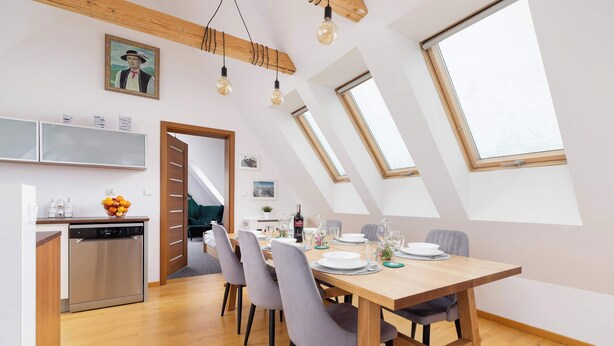 Una cucina moderna con lavastoviglie, un'area pranzo con tavolo e sedie in legno e lucernari.