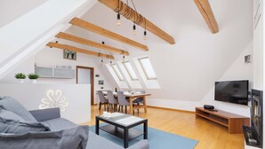 Un moderno loft con zona pranzo, soggiorno con divano e tavolino, televisione e lucernari.