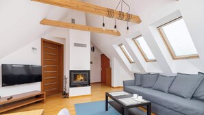 Un soggiorno moderno con camino, un divano, una televisione e un soffitto in legno.