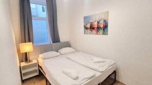 A hotel room with a bed, a nightstand, a lamp, and a painting on the wall. - Cozy 1BR Apt with Living Room & Garden (Vienna)