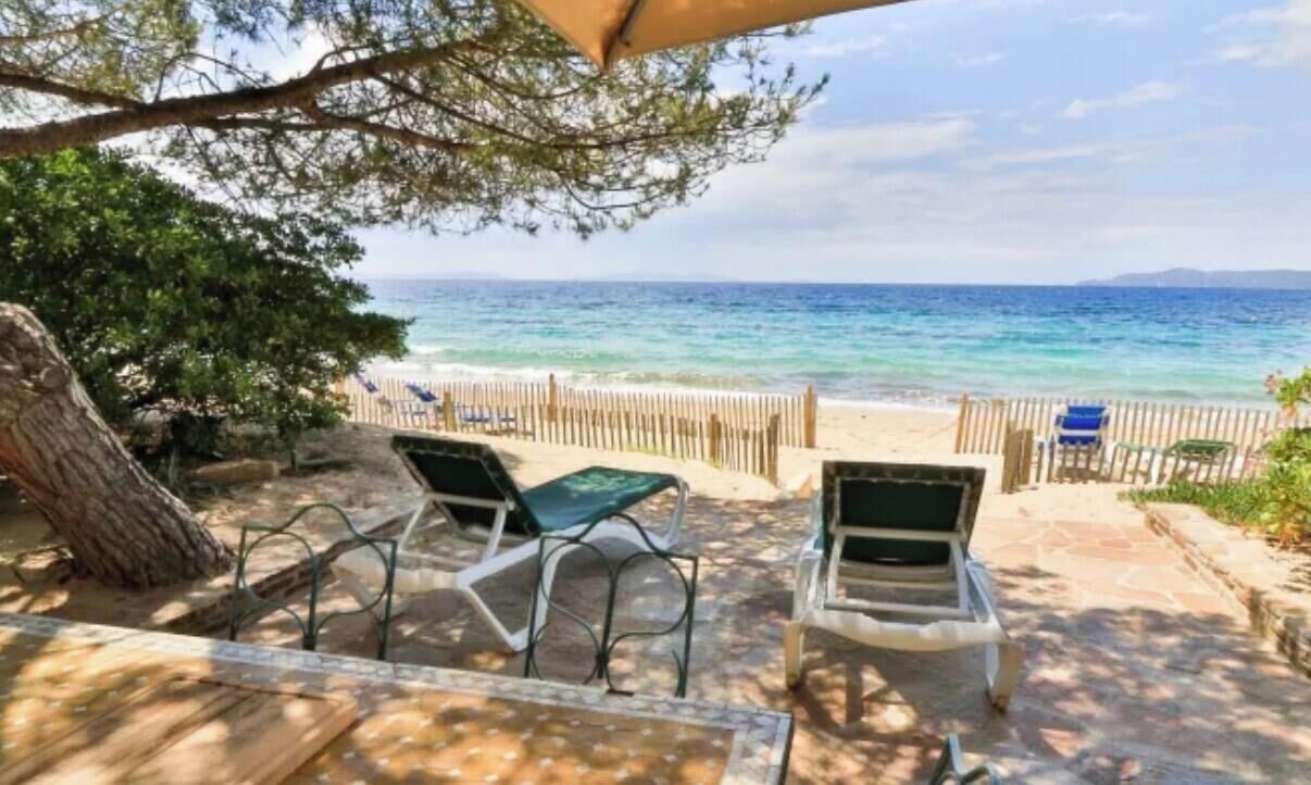 Eine Terrasse am Strand mit zwei Stühlen und einem Tisch, mit Blick aufs Meer.