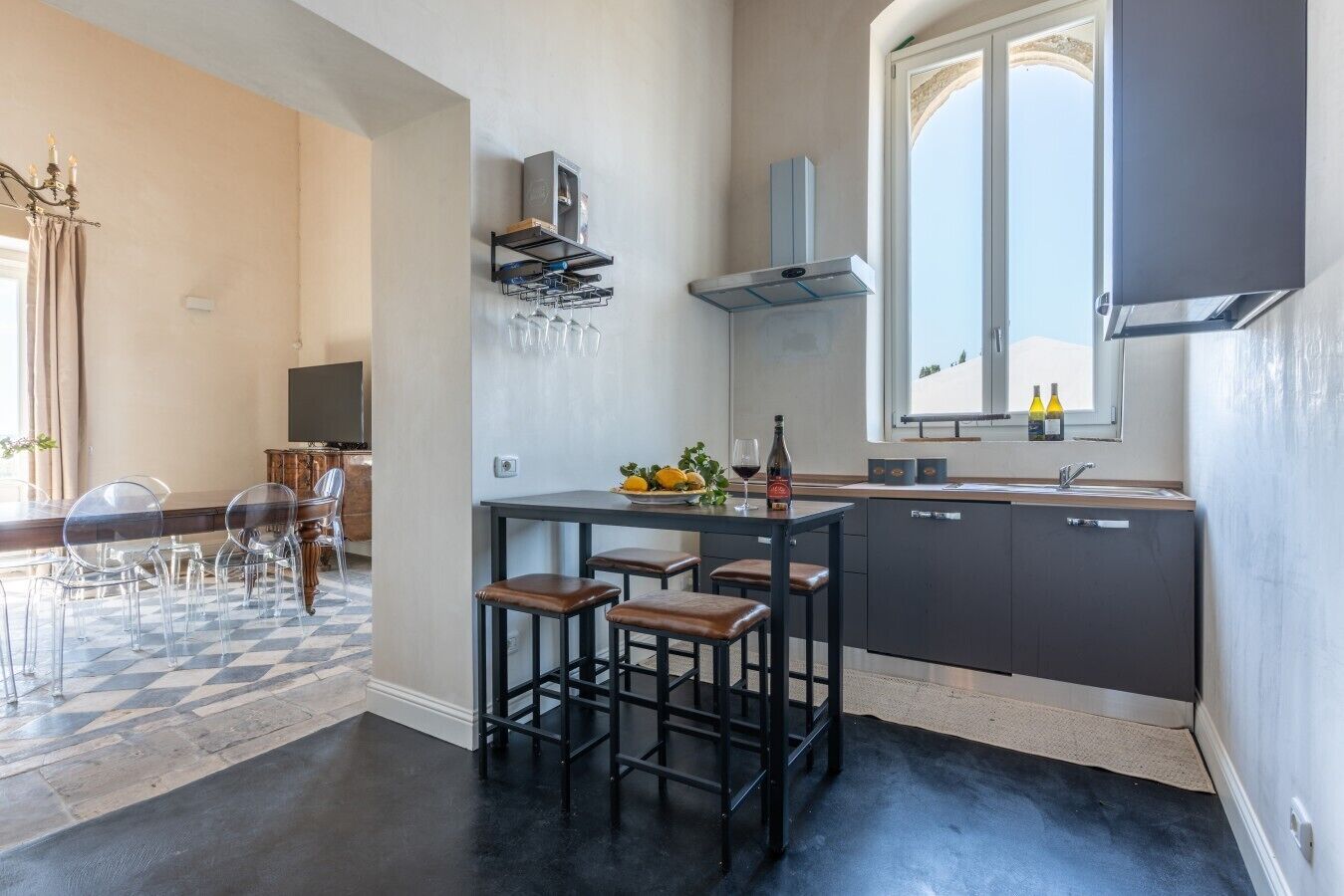 A modern kitchen with a dining area, bar stools, and a view of the outdoors.