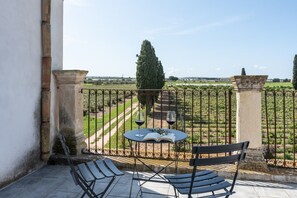 A balcony with a table, chairs, and a view of a vineyard. - Tenuta Santo Spirito - Wine Farm in a Historic Villa (Vittoria)