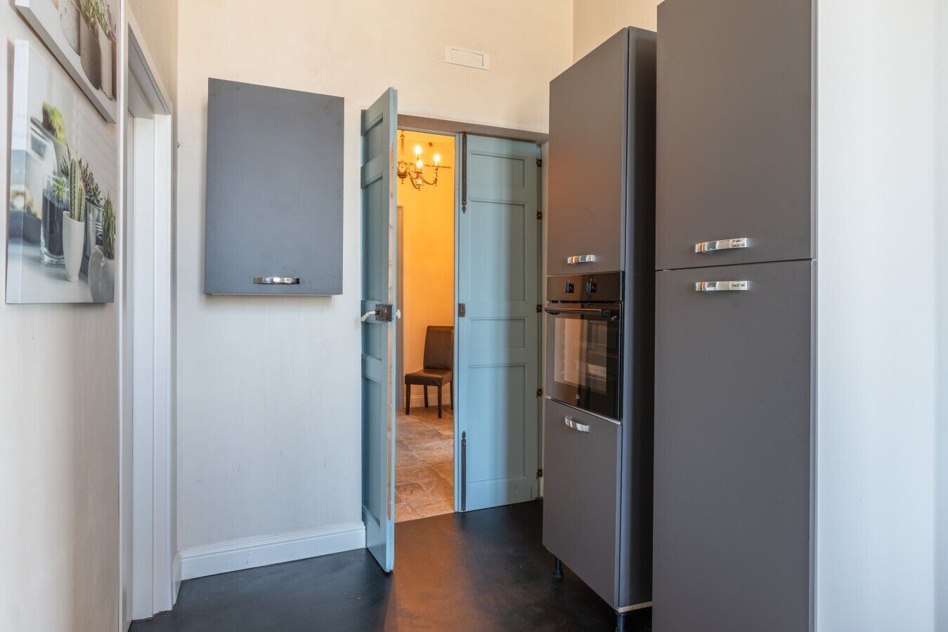 A kitchen with a refrigerator, oven, and a door leading to another room.