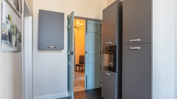 Cocina con refrigerador, horno y puerta que da a otra habitación.
