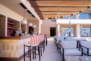 A bar area with a counter, bar stools, and hanging pendant lights. - Jaz Viva Villagio, Almaza Bay (Marsa Matrouh)