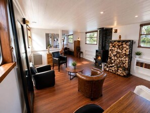 A spacious living room with a fireplace, wooden flooring, and a dog.