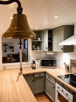 A kitchen with wooden cabinets, a microwave, a stove, and a hanging light fixture.
