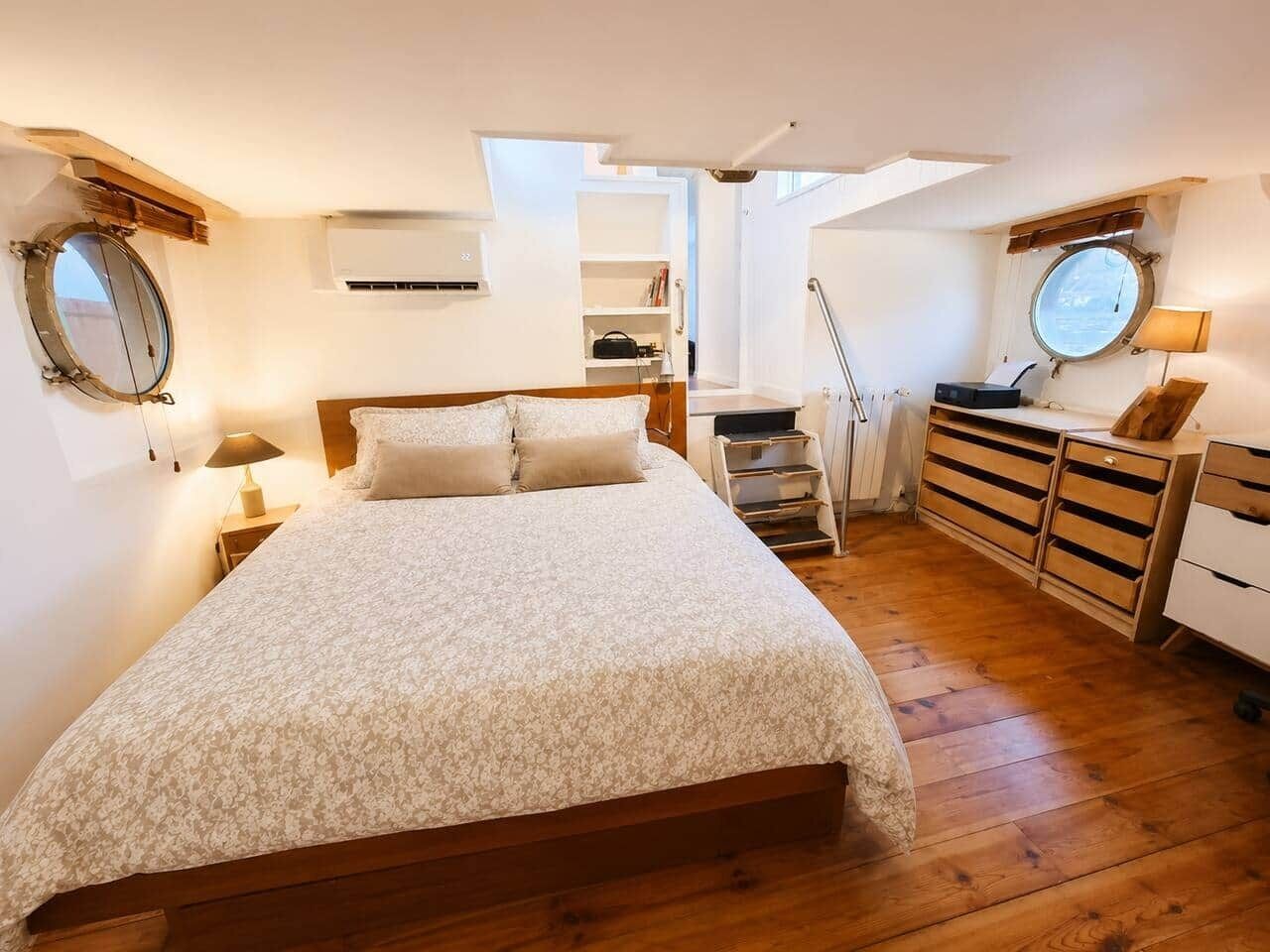 Een slaapkamer met een groot bed, een houten dressoir en een dakvenster.