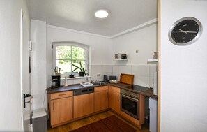 Une cuisine compacte avec des meubles en bois, un four encastré, un lave-vaisselle et une fenêtre.
