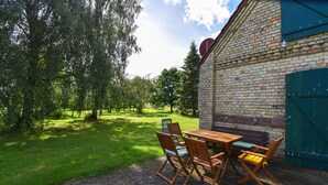 An outdoor seating area with a brick wall, a wooden table, and chairs. - Gorgeous home in Dobbertin with WiFi (Dobbertin)