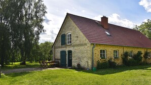 A stone building with a red roof, a green door, and a small garden area with a bench. - Gorgeous home in Dobbertin with WiFi (Dobbertin)