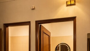 A bathroom with a toilet, sink, mirror, and a shower area. - Hotel Classio (Balichauki)
