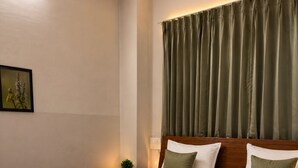 A neatly made bed with a wooden frame, a green throw blanket, and two pillows. - Hotel Classio (Balichauki)