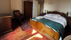 Une chambre à coucher avec un lit en bois, une chaise, une armoire et un miroir.