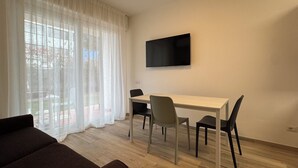 Huone, jossa on ruokapöytä, tuoleja, seinälle asennettu televisio ja sohva.