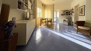 A spacious living area with a dining table, chairs, a sofa, and a ceiling fan. - Great flat with two terraces and parking (Bibione)