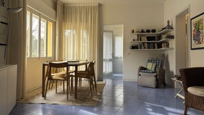 A room with a dining table, chairs, a bookshelf, and a sofa. - Great flat with two terraces and parking (Bibione)