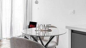 Ein modernes Zimmer mit Glastisch, Stuhl, Pendelleuchte und einem Schild mit der Aufschrift 'NETFLIX HOME'.